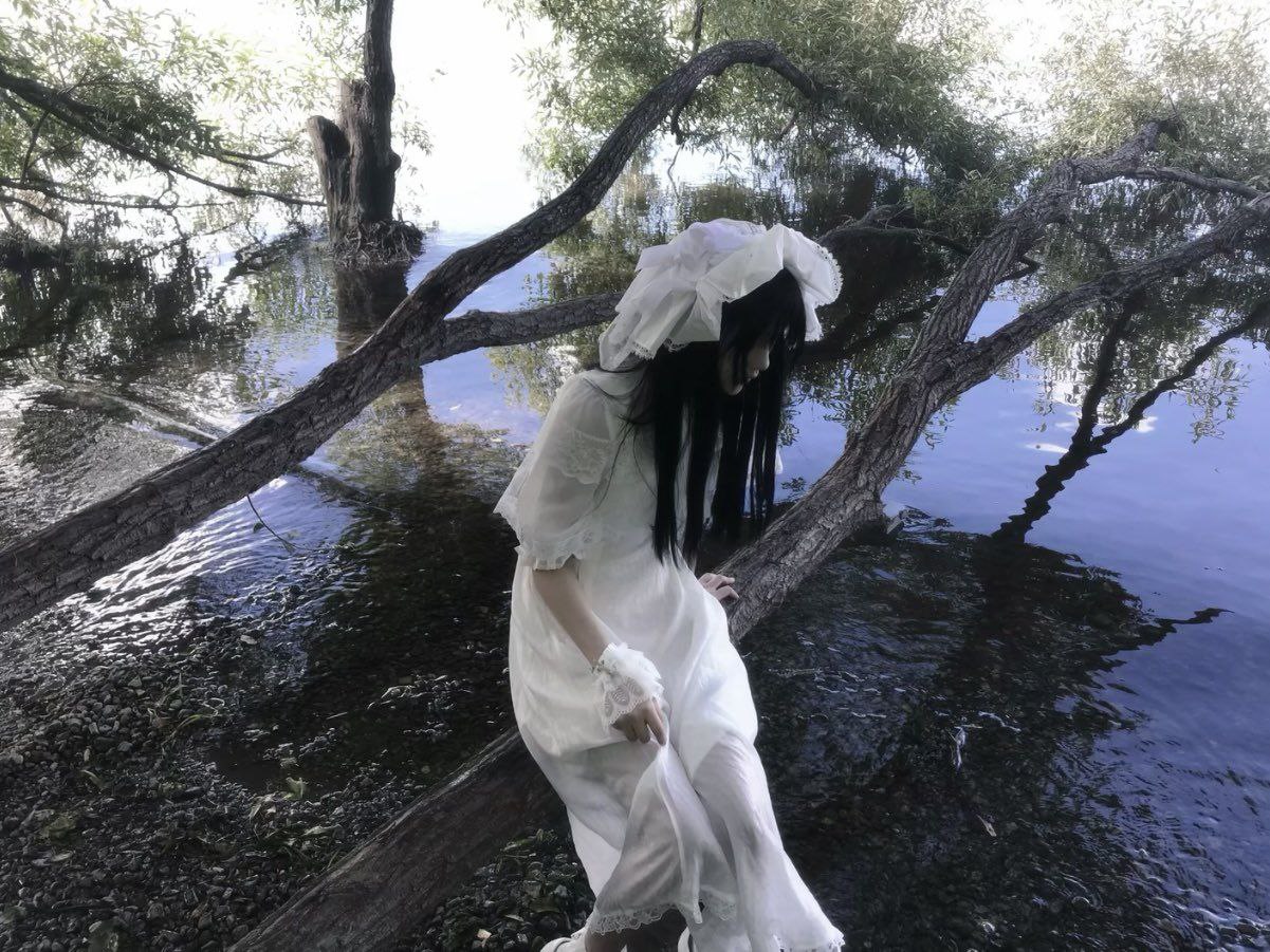 woman in a white dress sat on the floor in a forest